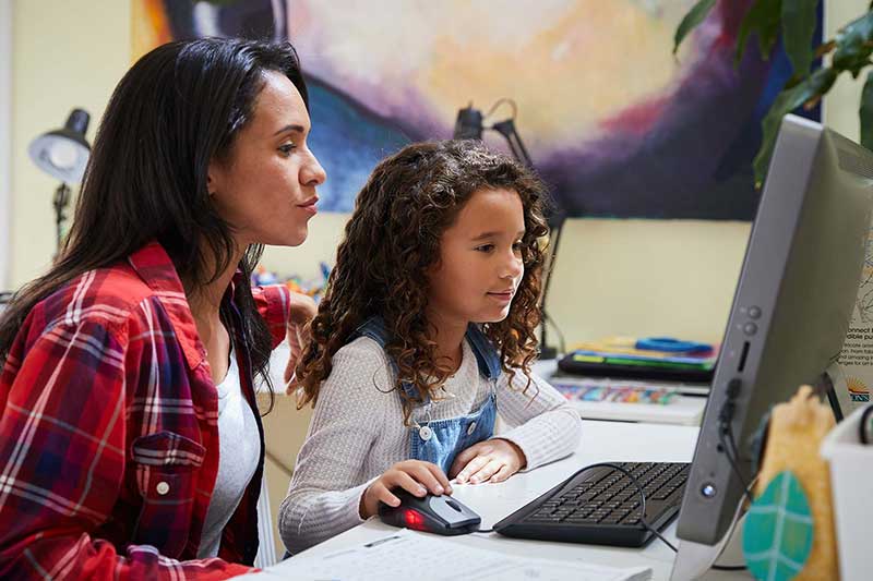 mother and young daughter using computer together