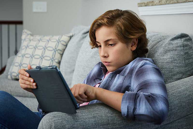 young boy using tablet on couch