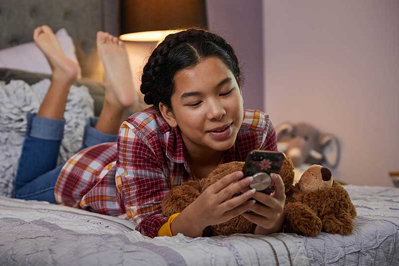 young girl using smartphone in bed