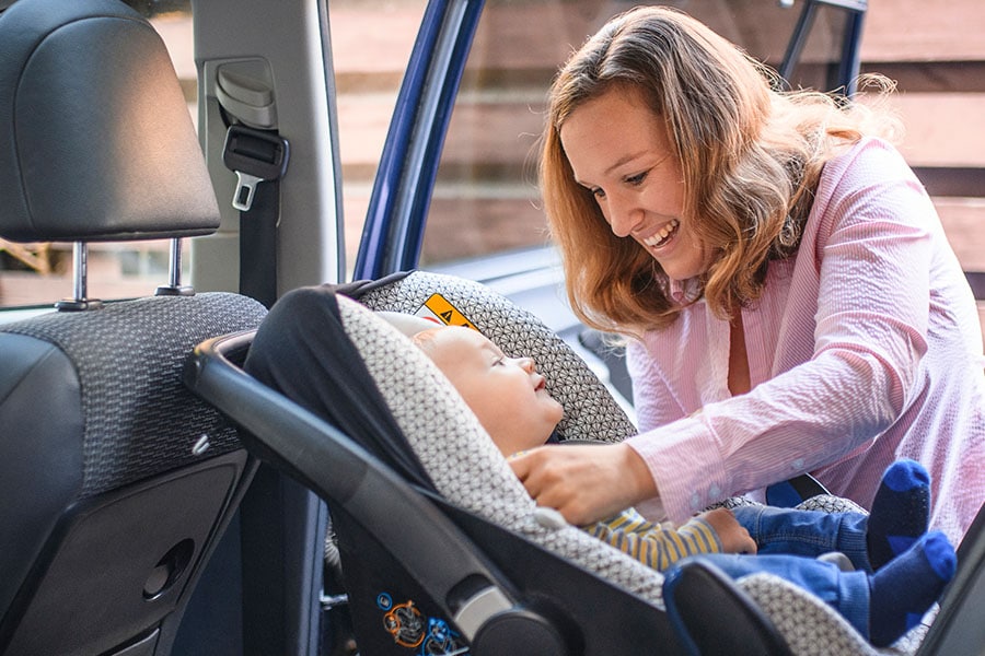 mom putting baby in car seat