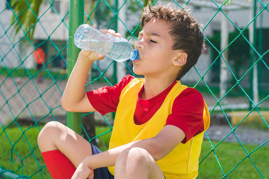 school age boy drinking water