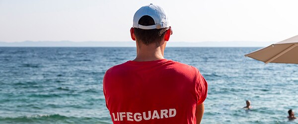 A photo of a lifeguard actively supervising kids swimming in the ocean.