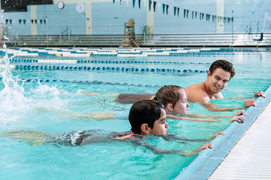 School age boy and girl take swim lessons to practice water safety and drowning prevention. 