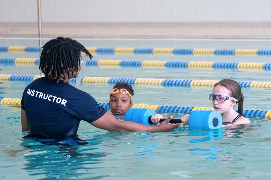 Two school age girls take swim lessons at a metro Atlanta YMCA to practice water safety.