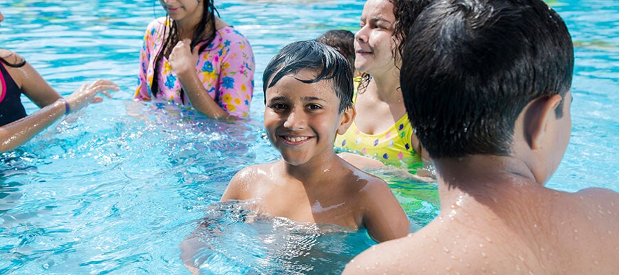 Photo of kids in pool practicing water safety by swimming safely