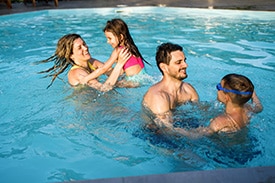 Photo of parents supervising and playing with kids in pool practicing pool-safety