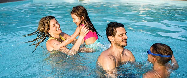 Photo of parents supervising and playing with kids in pool practicing pool-safety