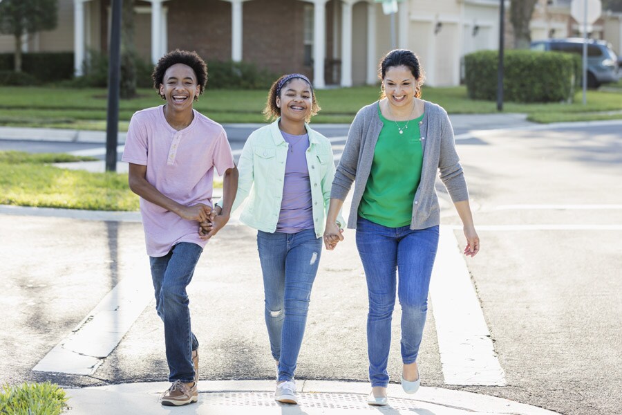 Two older, school-age children cross the street with mom.