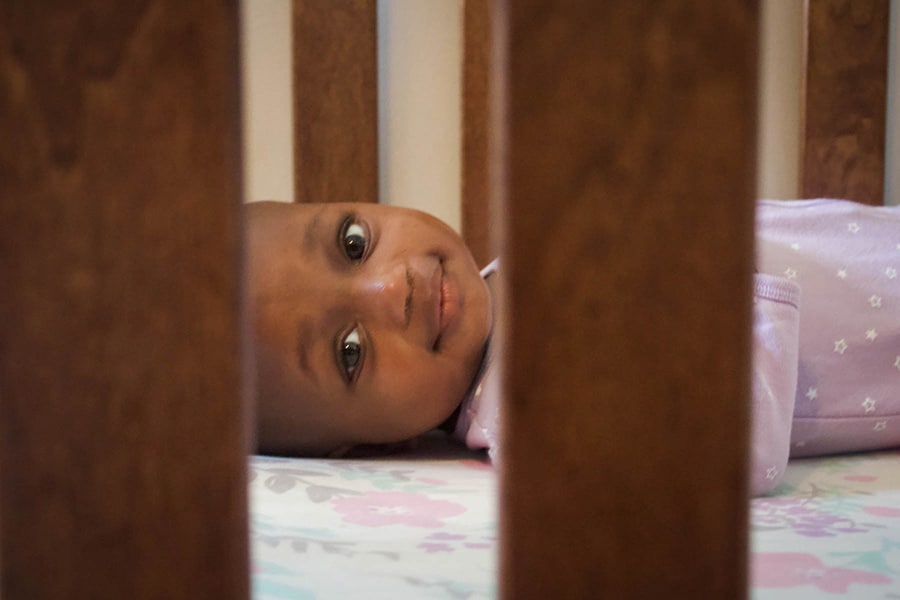 Infant sleeps on her back in a clear crib