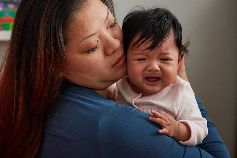 Mamá sosteniendo a su bebé que está llorando en sus brazos