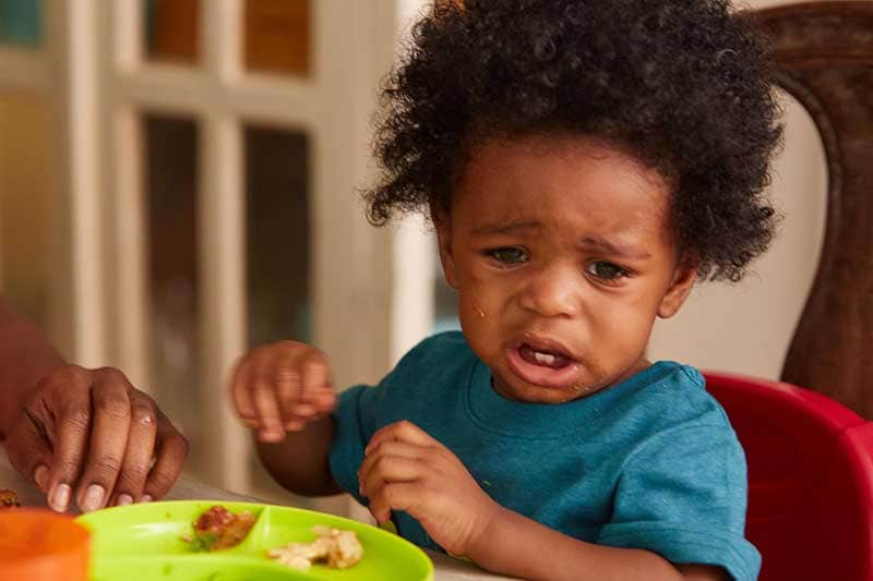 Niño pequeño llorando mientras come