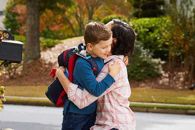 mom hugging son at bus stop